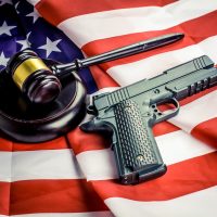 Wooden judge gavel and black color gun over USA flag Wooden judge gavel and black color gun over USA flag