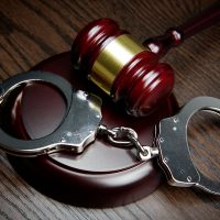 GAVEL AND HANDCUFFS ON WOOD