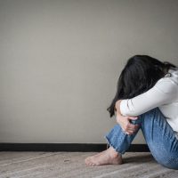 Anxiety disorder menopause woman, stressful depressed, panic attack person with mental health illness, headache and migraine sitting with back against wall on the floor in domestic home