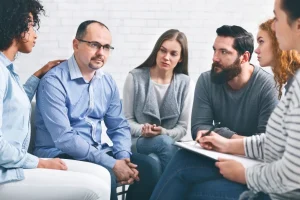 Middle-aged man sitting at support group session, telling about alcohol addiction